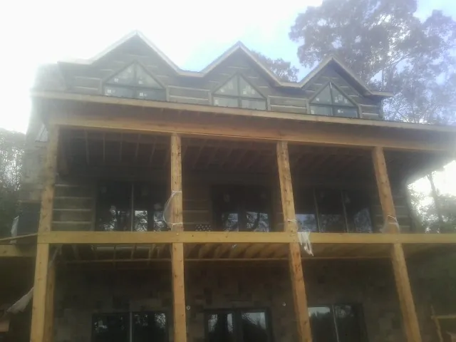 Dormers and porch framing on a large log home under construction — Roof Coating work by our crew in Rosholt
