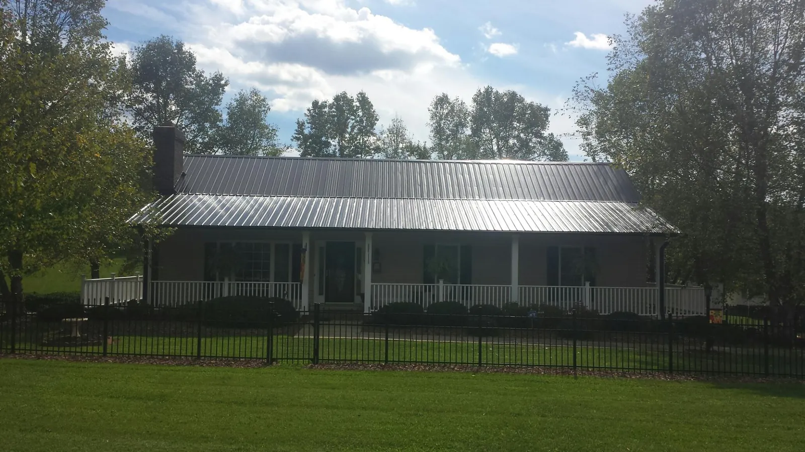 Gray metal roof on a brick ranch with a full width front porch — Gutter Guard Installation work by our crew in Rosholt