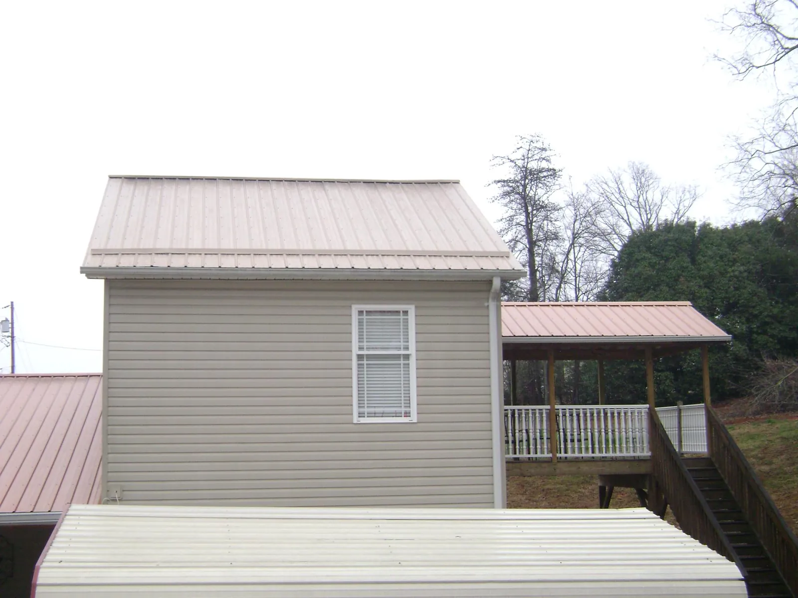 Tan metal roofs on a two story addition and attached porch, from a Roof Replacement job in Rosholt