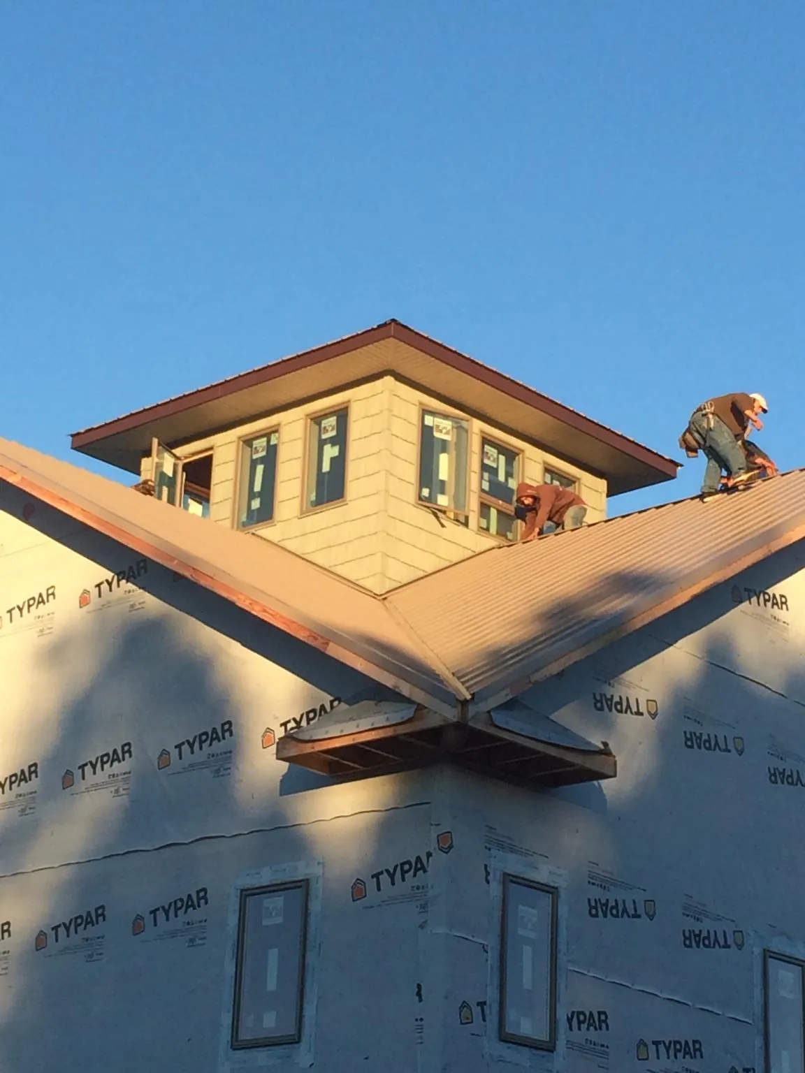 Roofers working around a rooftop cupola on a new metal roof at sunset — Roof Waterproofing in Rosholt by Roofing Brothers